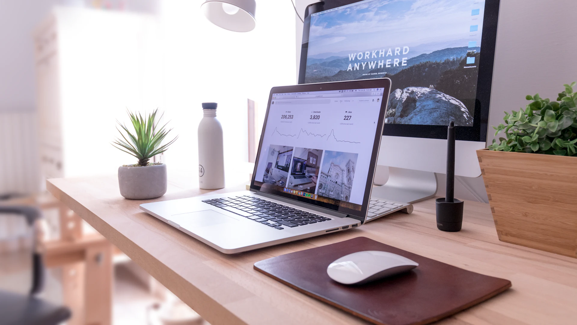 Escritorio de diseño con una laptop y una computadora mostrando un sitio web
